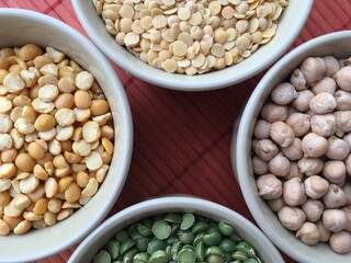 Round bowls with legumes, peas, chickpeas and lentils on a red background. A bowl of food on a plate. High quality photo