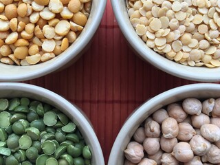 Round bowls with legumes, peas, chickpeas and lentils on a red background. A bowl of food on a plate. High quality photo