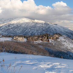 Square crop Pristine landscape of Wasatch Mountains with houses on its snow covered terrain