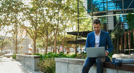Businessman using a laptop while sitting outside his office building