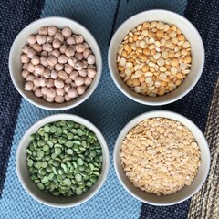 Bowl with legumes stand on a woven multi-colored tablecloth. Gastronomic background for decoration and design of the kitchen, dining room, shop, restaurant.