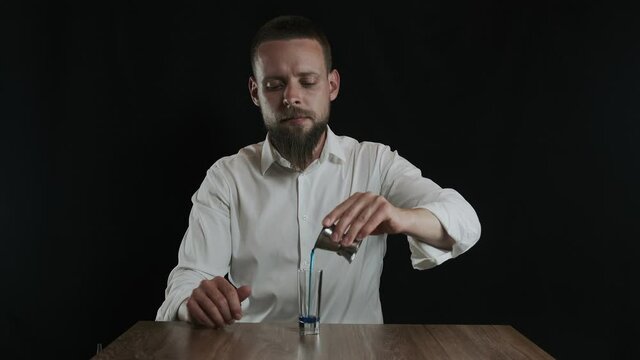Bartender pouring blue curacao liquor into glass from jigger