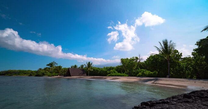 Lockdown time lapse shot of Hawaiian hut by trees at beach against blue sky on sunny day - Big Island, Hawaii