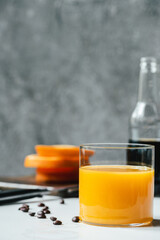 selective focus of orange juice in glass near cold brew coffee and coffee beans on white table