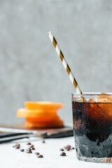 selective focus of cold brew coffee with ice and drinking straw on white table