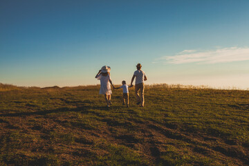 Little boy walking with parents, holding their hands