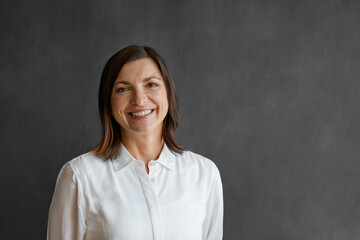 Fototapeta premium Smiling businesswoman standing in front of a blank office chalkboard