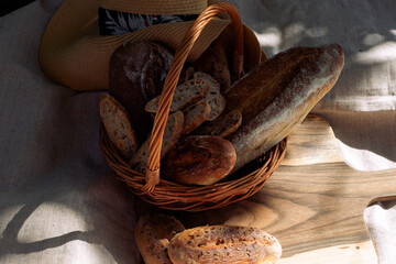 wicker basket with handmade bread, cutting board, straw hat