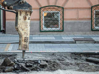 Jackhammer mounted on a renovation vehicle, with a pneumatic drill perforating the asphalt of an urban road being renovated on a street construction site