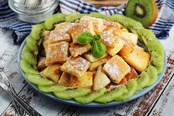 Austrian dessert Kaiserschmarrn served with sugar powder and kiwi fruit