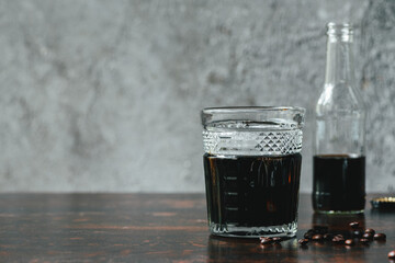 selective focus of cold brew coffee in bottle and glass near coffee beans