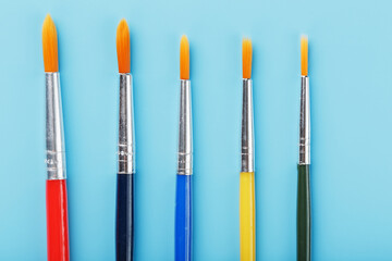 Multi-colored paintbrushes on a blue background.