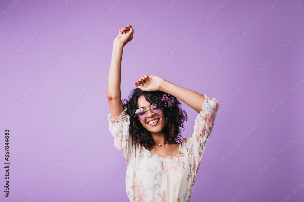 Canvas Prints Indoor portrait of magnificent african woman standing on purple background with hands up. Studio shot of female model with wavy hair expressing good emotions.