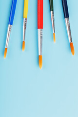 Multi-colored brushes for drawing and art on a blue background.
