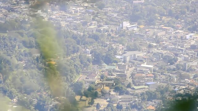 The city in the mountains is shot through a blurry grid of waving branches. A combination of statics and dynamics. Sri Lanka, outskirt of Kandi
