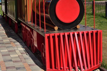 A model of a steam locomotive made of wood painted in bright color in a city park