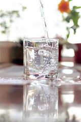 Pouring cold clean water into a glass goblet on a sunny, hot day.