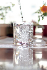 Pouring cold clean water into a glass goblet on a sunny, hot day.