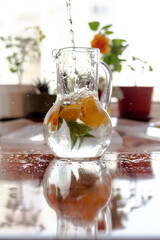 A decanter with cold, refreshing lemonade made from orange and mint on a hot summer day