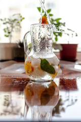 A decanter with cold, refreshing lemonade made from orange and mint on a hot summer day