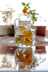 A decanter with cold, refreshing lemonade made from orange and mint on a hot summer day
