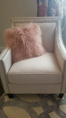 Vertical Bedroom interior with faux fur throw pillow on a white upholstered armchair