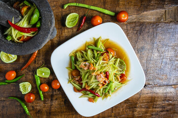 .Cooking Thai food, papaya salad and papaya salad in a dish with a serving on a wooden table.