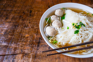 .Noodle and meatballs in a bowl on a wooden table