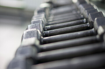 Many dumbbells on a specialized rack for dumbbells. Sport, fitness, weightlifting, healthy lifestyle. Exercise in the fitness room.