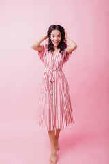 Full-length shot of barefooted girl in long dress laughing to camera. Indoor photo of amazing...