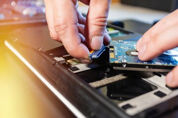 Installing hdd on an old laptop, on a black background with flare light. Concept of upgrading a laptop computer. Close up view