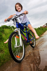 Fototapeta na wymiar Child, boy, riding bike in muddy puddle, summer time