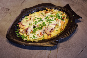 Delicious fried fish with cheese, cream, mushrooms, onion served in the fish-shape plate on the gray baclground. Traditional Mediterranean, greece, italian or french meal. Icelandic or Norwegian dish.