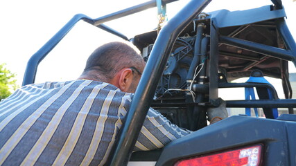 Unrecognizable repairman or mechanic repairing vehicle. Male repairer fixing automobile. Auto master doing his work outdoor at sunny day. Man engaged in servicing auto. Car service. Slow mo Close up