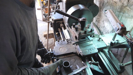 Unrecognizable man working with old workbench in his garage or workshop. Mechanic using lathe for metal processing. View on turning work. Slow motion Close up