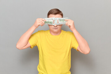 Mature man with glasses is covering his eyes with money