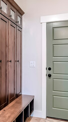 Vertical Panelled fire door with black knobs and lock adjacent to a tall vintage cabinet