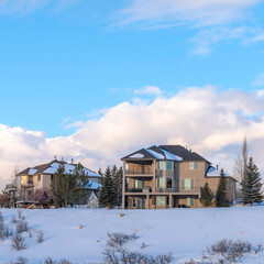 Square crop Homes against clouds and blue sky at Wasatch Mountains neighborhood in winter