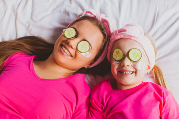 Top view woman and girl faces with cucumber slices on eyes