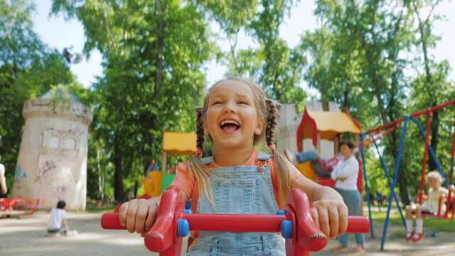 Cute pretty child rides on balancing swing, little girl laughing and having fun