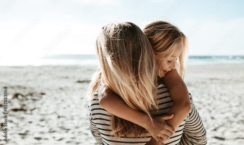 Wall mural mother carrying daughter along the beach