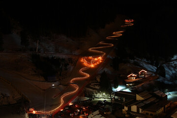 Night long exposure shot of winter ski show. Skiers with torches sliding down and creating a heart...