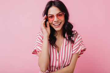 Blithesome caucasian woman with pretty smile touching her glasses. Studio portrait of funny...