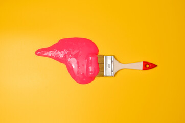 Shot of a brush with pink sticky slime on yellow background. Minimalism in photography, concept creative picture.