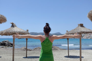 Concept of social distancing on the beach, umbrellas 2 m apart and a woman with outstretched arms measuring the social distance on the beach during the summer in the Mediterranean Sea.