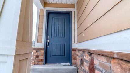 Panorama Home facade with blue panel door and melting snow on the doorstep and entryway