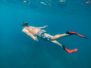 man in underwater in flippers looking at sea bottom