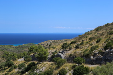 Fototapeta premium panorama landscape scenic view of isolated green and yellow vegetation mountain with blue sea water and sky background on beautiful and colorful Mallorca island in Spain