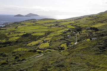 Fototapeta na wymiar Vue panoramique sur la mer à l'horizon, les prairies verdoyantes, les collines et les vallées, et quelques maisons blanches au sud-ouest de l'Irlande dans le compté de Kerry.