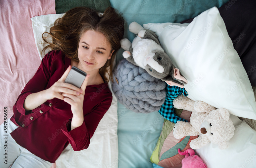 Wall mural Top view of happy young girl smiling and taking selfie on bed, online dating concept.